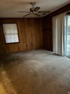 unfurnished room with ceiling fan and wood walls