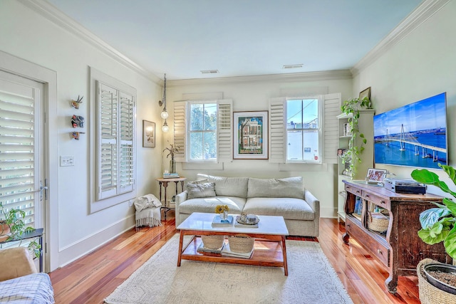 living area featuring visible vents, crown molding, baseboards, and wood finished floors