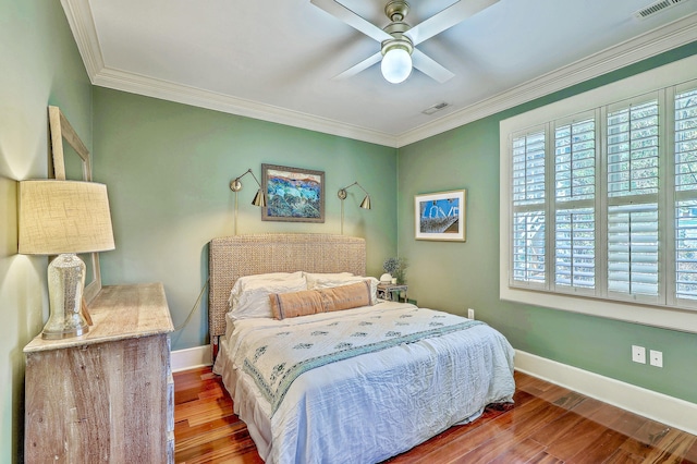 bedroom with baseboards, wood finished floors, and crown molding