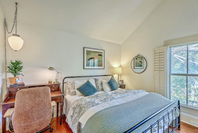 bedroom with vaulted ceiling, wood finished floors, and baseboards