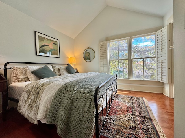 bedroom with high vaulted ceiling and wood finished floors