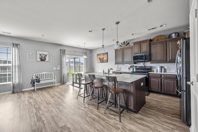 9009 Chato Ct, Summerville, SC 29483 - kitchen featuring appliances with stainless steel finishes, a kitchen bar, a sink, light wood-style floors, and an island with sink