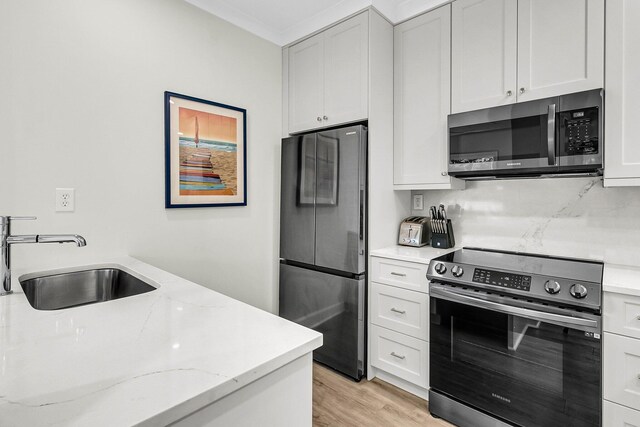 kitchen with light hardwood / wood-style floors, white cabinetry, sink, and stainless steel appliances