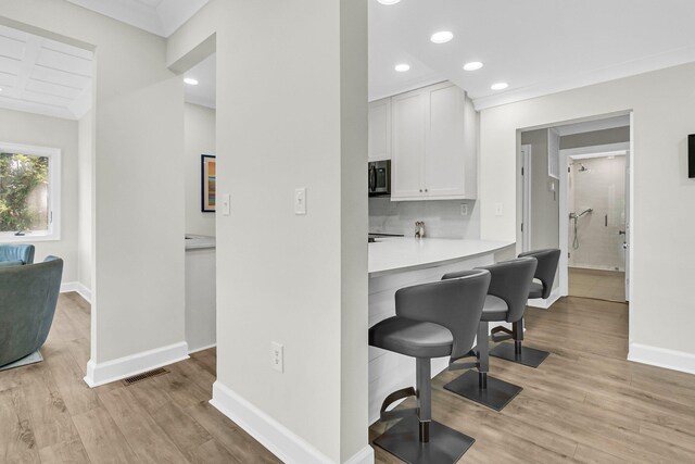 kitchen with a breakfast bar area, light wood-type flooring, and white cabinetry