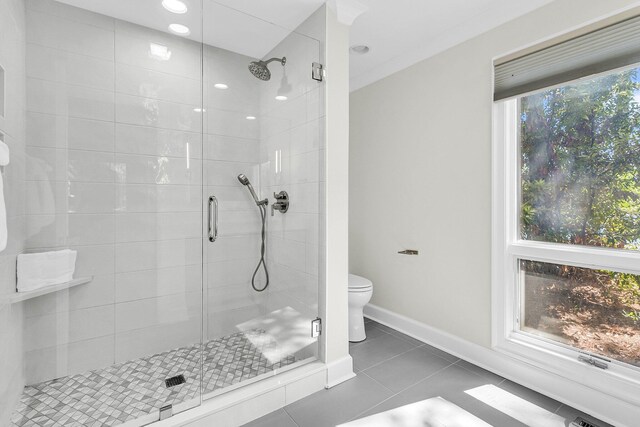 bathroom featuring walk in shower, a healthy amount of sunlight, tile patterned flooring, and toilet