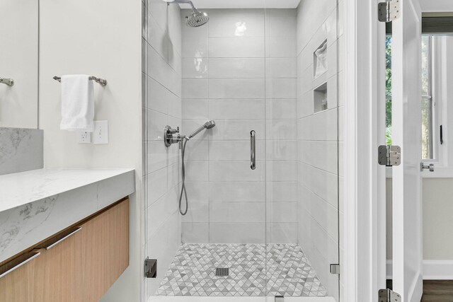 bathroom with vanity, a shower with door, and a wealth of natural light