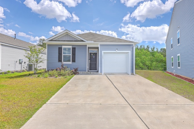 view of front of property with an attached garage, a front yard, driveway, central AC, and a shingled roof