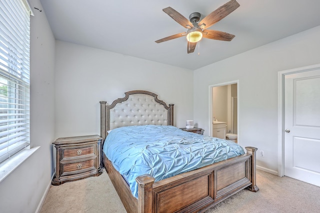bedroom featuring light colored carpet, ensuite bath, baseboards, and ceiling fan