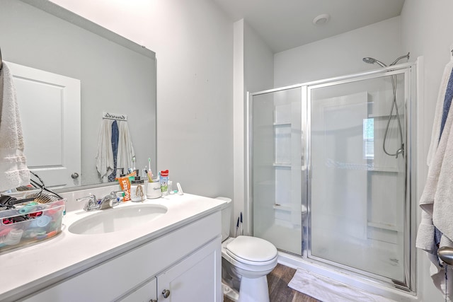 full bath featuring a shower stall, vanity, toilet, and wood finished floors