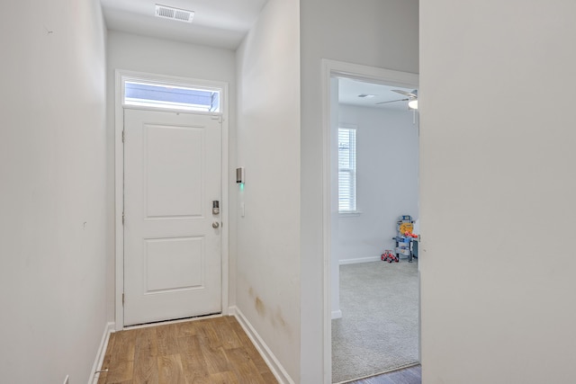 doorway to outside featuring plenty of natural light, baseboards, light wood-style flooring, and a ceiling fan