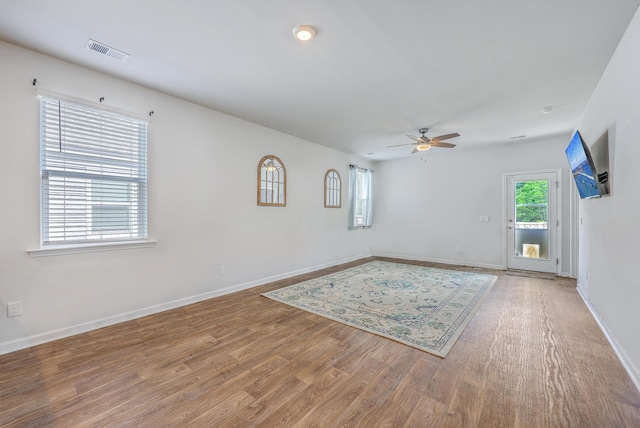 spare room with a ceiling fan, light wood-style flooring, and baseboards