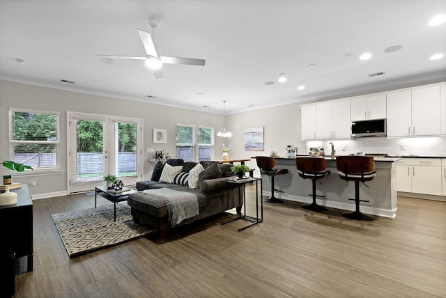 bedroom with dark wood finished floors, crown molding, access to exterior, baseboards, and recessed lighting
