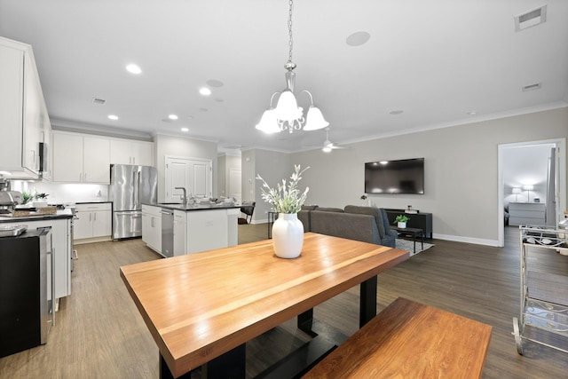 dining room featuring a chandelier, crown molding, baseboards, recessed lighting, and light wood-style floors