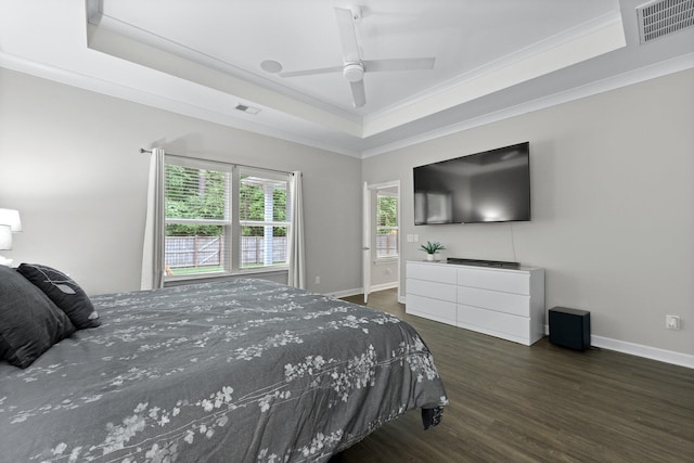 bedroom with a tray ceiling, wood finished floors, ornamental molding, baseboards, and a ceiling fan