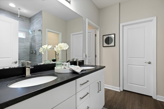 full bath with a shower stall, wood finished floors, double vanity, and baseboards