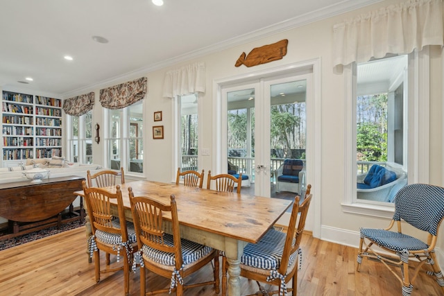 dining room with light wood finished floors, baseboards, ornamental molding, and french doors