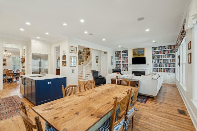 dining space with light wood-type flooring, stairs, a fireplace, and visible vents