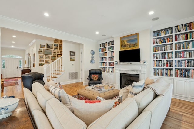 living room featuring stairway, light wood-type flooring, visible vents, and crown molding