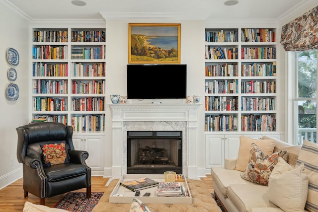 living area with light wood-type flooring, a fireplace, and ornamental molding