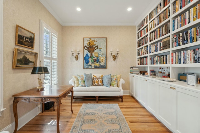 sitting room featuring ornamental molding, light wood-style flooring, and baseboards