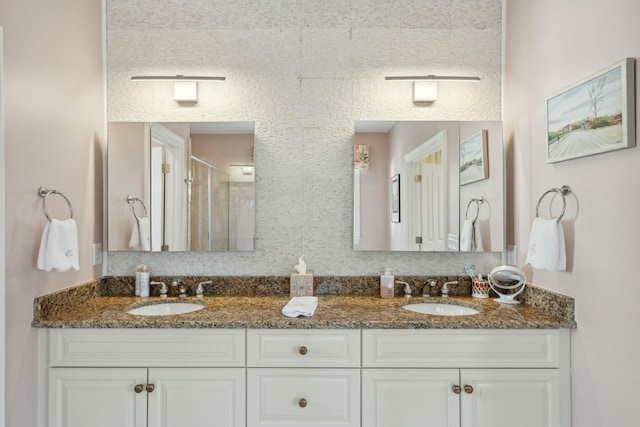 full bathroom featuring double vanity, a stall shower, and a sink