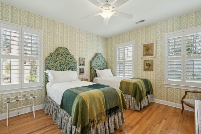 bedroom with wallpapered walls, visible vents, baseboards, and light wood finished floors