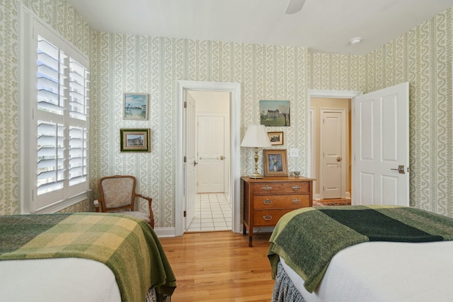 bedroom featuring light wood-type flooring, wallpapered walls, and multiple windows