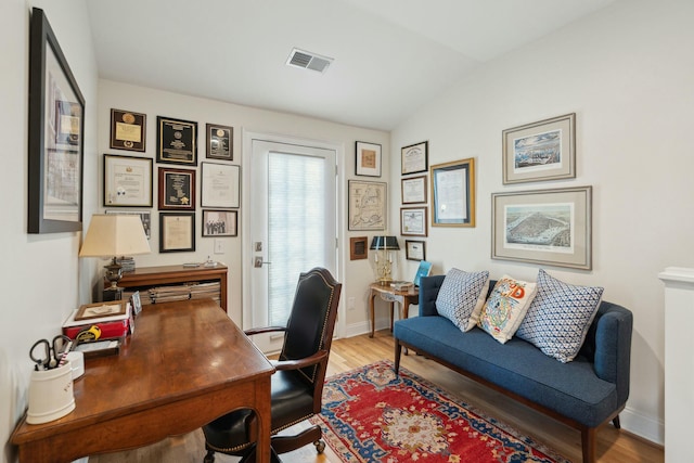 home office with vaulted ceiling, wood finished floors, visible vents, and baseboards