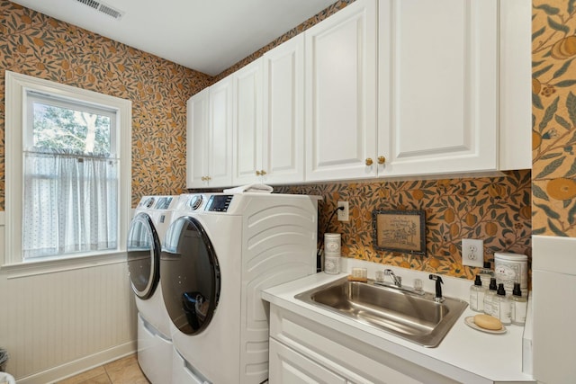 washroom featuring cabinet space, a sink, washer and dryer, and wallpapered walls