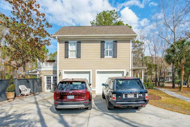 view of front of home with a garage, concrete driveway, and roof with shingles