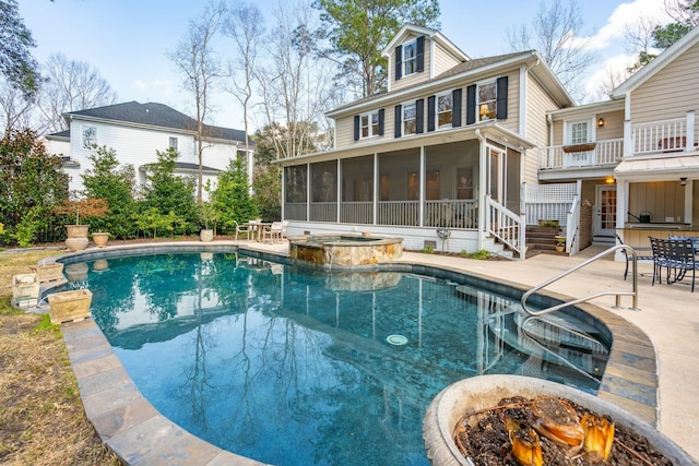 view of swimming pool with a sunroom, a pool with connected hot tub, and a patio