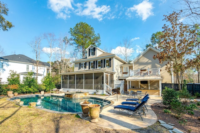 back of property featuring a patio, a pool with connected hot tub, a sunroom, fence, and a balcony