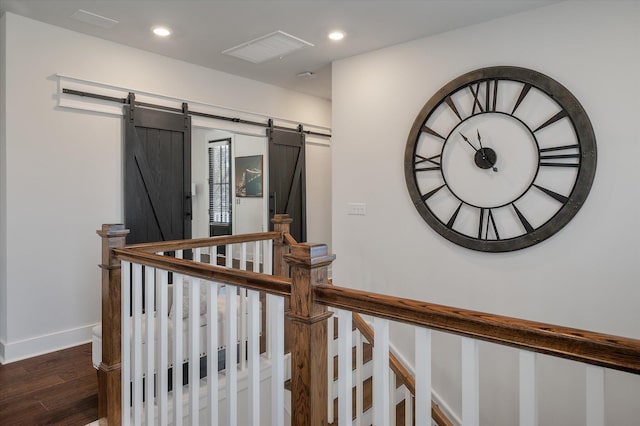 corridor with dark wood-style flooring, recessed lighting, a barn door, and visible vents