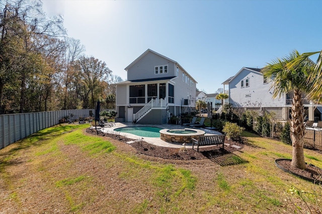 rear view of house featuring stairs, a sunroom, a pool with connected hot tub, a yard, and a fenced backyard