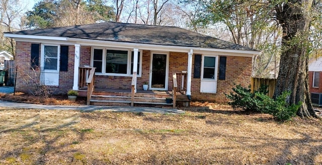 view of front of house with covered porch, central AC, and brick siding