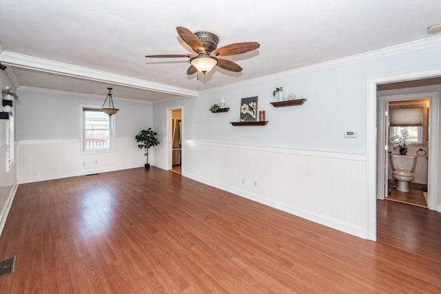 unfurnished room featuring crown molding, a wainscoted wall, ceiling fan, and wood finished floors