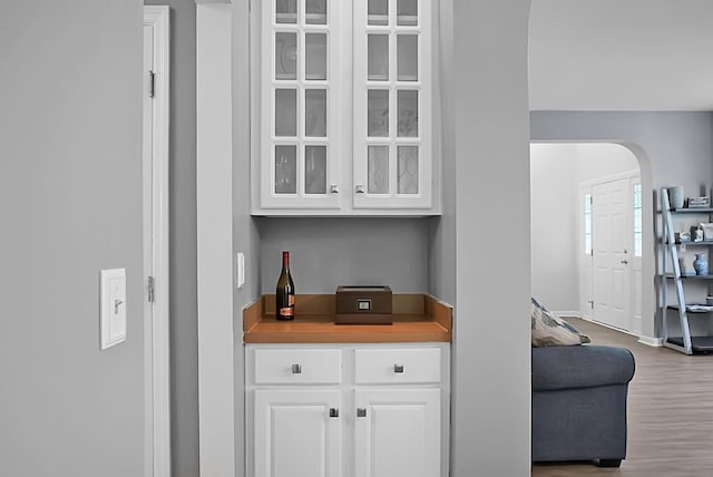 bar with wood finished floors, arched walkways, and baseboards