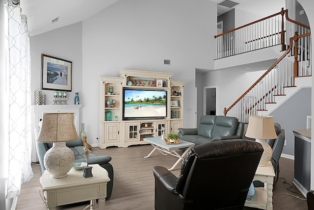 living room featuring high vaulted ceiling, stairs, wood finished floors, and baseboards