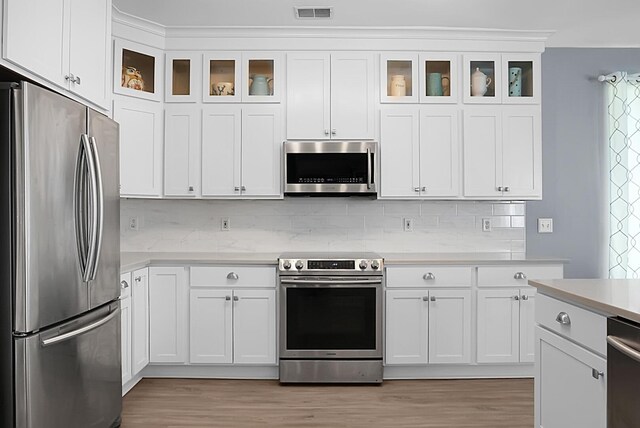 kitchen featuring stainless steel appliances, light countertops, light wood finished floors, and white cabinets