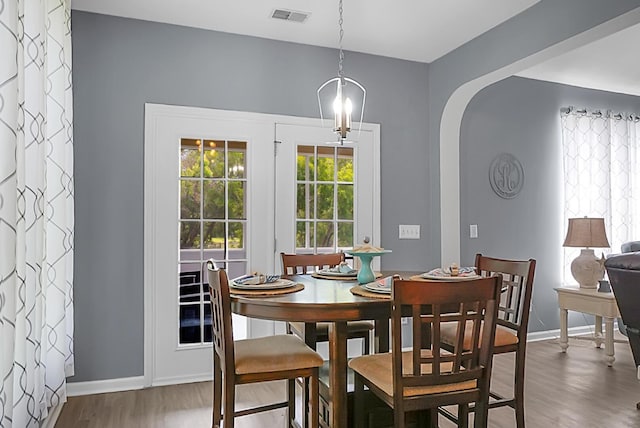 dining space featuring wood finished floors, baseboards, and arched walkways