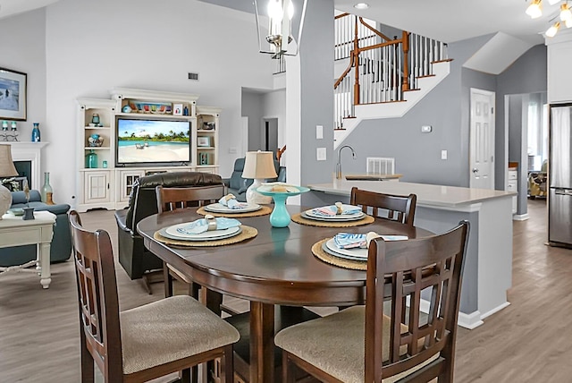 dining area featuring light wood-style flooring, stairs, a high ceiling, and baseboards