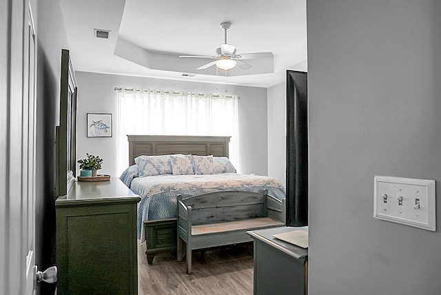 bedroom featuring a tray ceiling, light wood-type flooring, and a ceiling fan