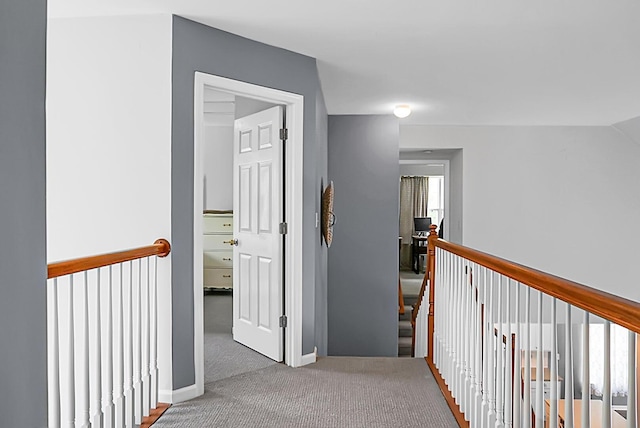 corridor with an upstairs landing, carpet flooring, and baseboards