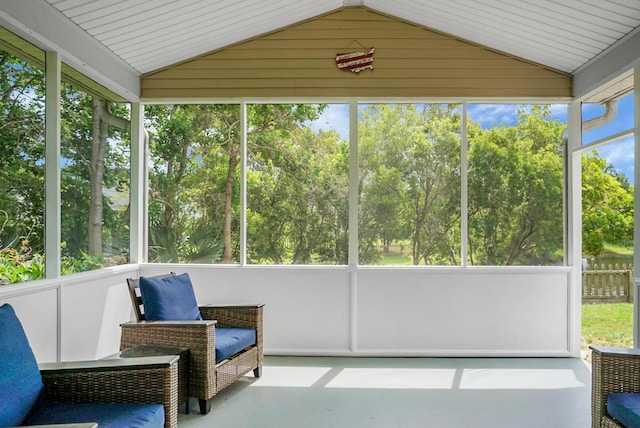 sunroom / solarium featuring lofted ceiling, healthy amount of natural light, and view of scattered trees
