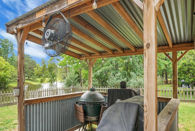 wooden terrace with fence, view of scattered trees, a water view, and grilling area