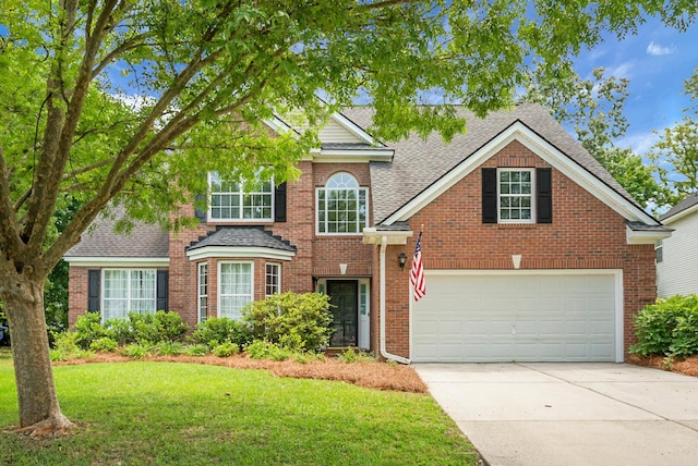 view of front of property with driveway, a shingled roof, a front yard, and brick siding