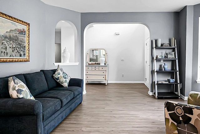 living area with wood finished floors, arched walkways, and baseboards
