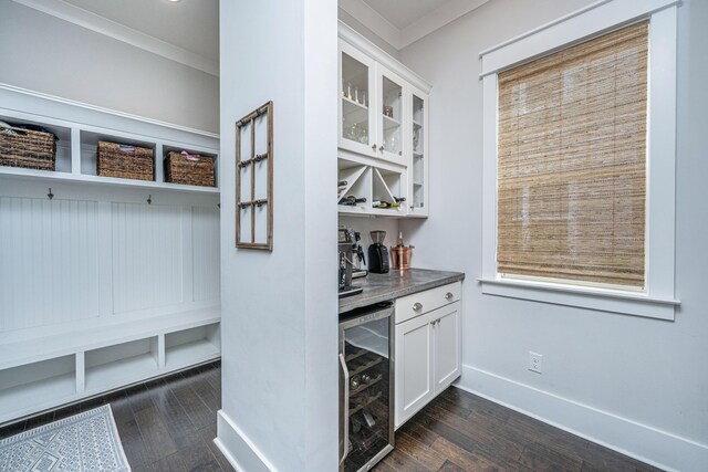 mudroom with beverage cooler, dark wood-style floors, crown molding, a dry bar, and baseboards
