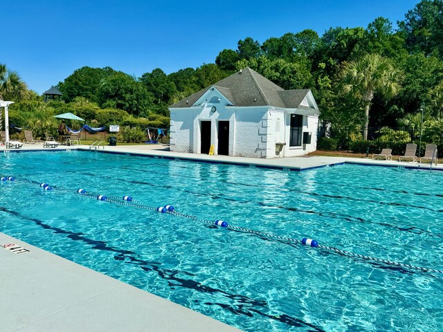 community pool with a patio area and view of scattered trees