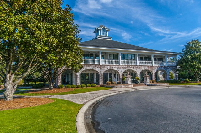 view of front of home featuring a balcony and a front lawn